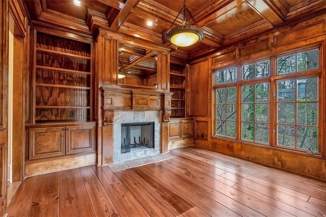 unfurnished living room featuring coffered ceiling, wooden ceiling, a fireplace, wooden walls, and built in features