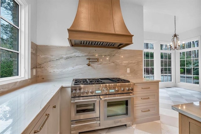 kitchen featuring range with two ovens, backsplash, a chandelier, light floors, and premium range hood
