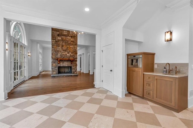 interior space with a chandelier, a fireplace, ornamental molding, light floors, and a sink