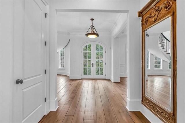 foyer with plenty of natural light, french doors, crown molding, and wood-type flooring