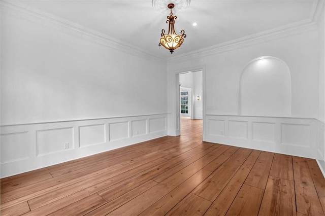 empty room with a decorative wall, ornamental molding, and hardwood / wood-style flooring