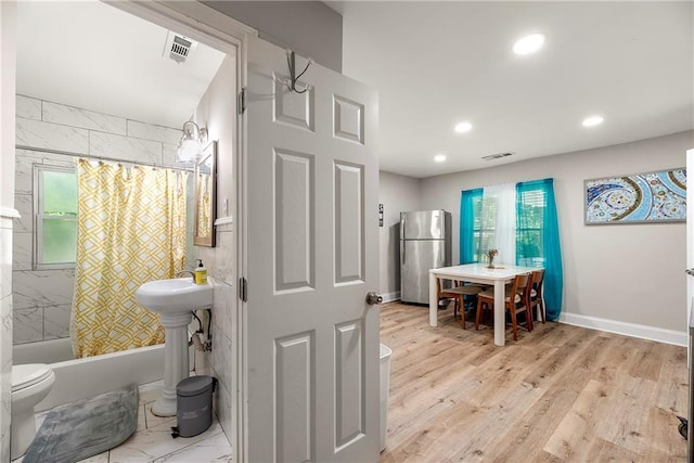 bathroom with toilet, shower / bath combo with shower curtain, and hardwood / wood-style floors