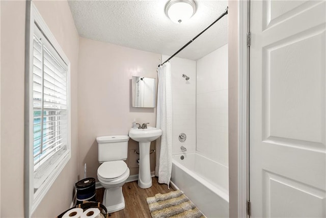 full bathroom with sink, a textured ceiling, shower / bathtub combination with curtain, hardwood / wood-style floors, and toilet