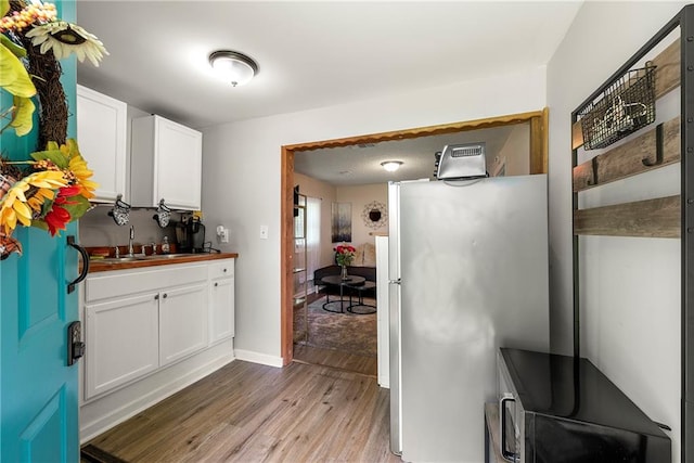 kitchen with refrigerator, white cabinetry, light hardwood / wood-style flooring, and wooden counters