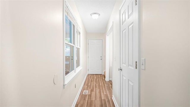 corridor featuring a textured ceiling and light hardwood / wood-style flooring