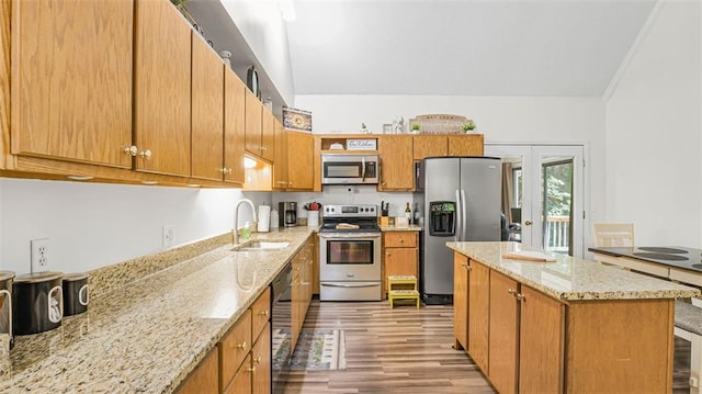 kitchen featuring appliances with stainless steel finishes, light wood-type flooring, light stone counters, crown molding, and sink