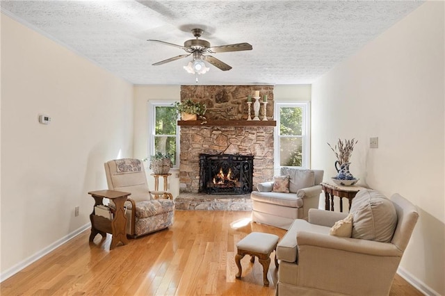 479 Deerpath Dr, Sautee Nacoochee, GA 30571 - living room with a stone fireplace, a textured ceiling, light wood finished floors, and a ceiling fan