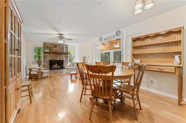 479 Deerpath Dr, Sautee Nacoochee, GA 30571 - dining room with a ceiling fan, light wood finished floors, a textured ceiling, and a fireplace