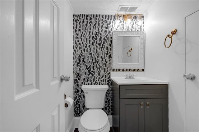 bathroom with a textured ceiling, toilet, vanity, visible vents, and ornamental molding