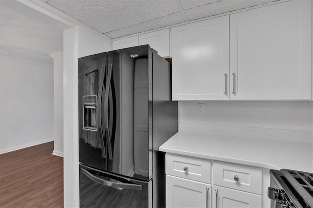 kitchen with wood finished floors, white cabinetry, baseboards, light countertops, and black fridge