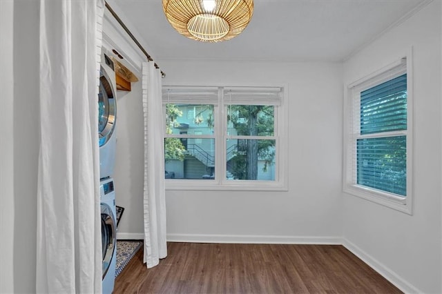 unfurnished bedroom with stacked washer / dryer, baseboards, and wood finished floors