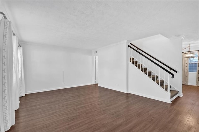 unfurnished living room featuring baseboards, dark wood-style flooring, stairway, and an inviting chandelier