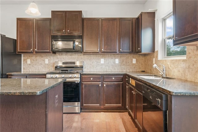 kitchen with black appliances, sink, hanging light fixtures, and dark stone counters