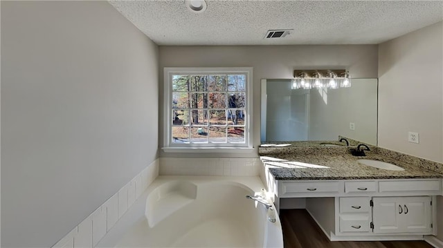 bathroom with a bathing tub, vanity, a textured ceiling, and hardwood / wood-style flooring