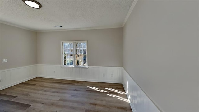 unfurnished room featuring wood-type flooring, ornamental molding, and a textured ceiling