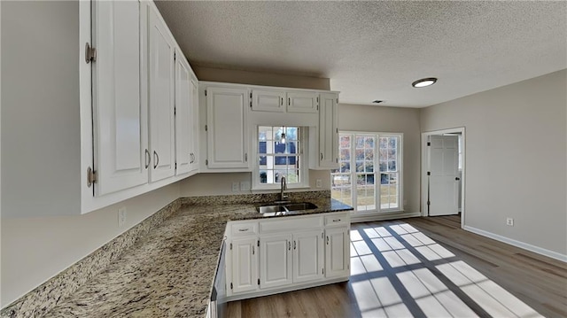 kitchen with white cabinetry, sink, dark stone counters, and a textured ceiling