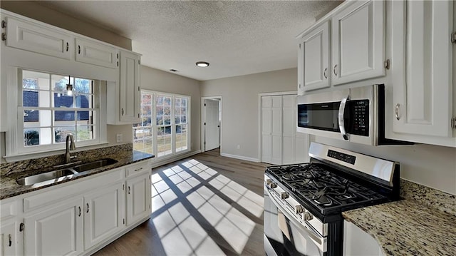 kitchen featuring white cabinets, sink, appliances with stainless steel finishes, and dark stone counters