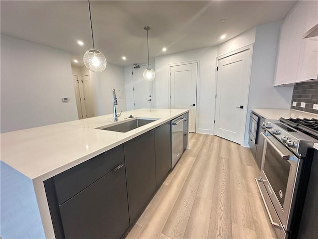 kitchen featuring a sink, modern cabinets, a center island with sink, and stainless steel appliances