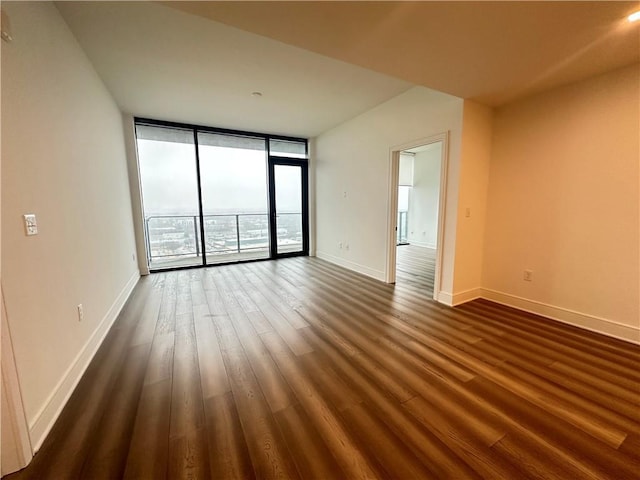 unfurnished room with baseboards, dark wood-style floors, and expansive windows