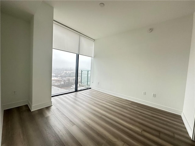 empty room featuring baseboards, floor to ceiling windows, and dark wood finished floors