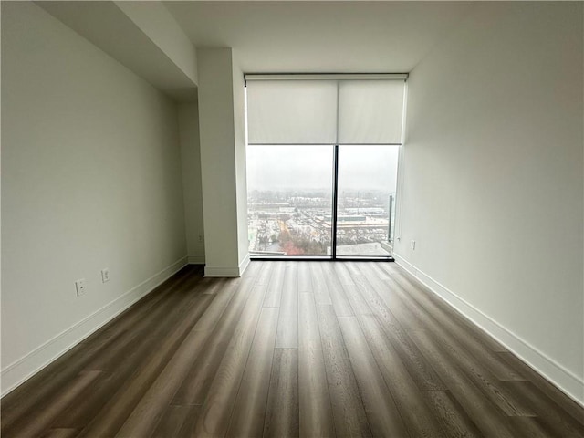 unfurnished room featuring baseboards, floor to ceiling windows, and dark wood-style flooring