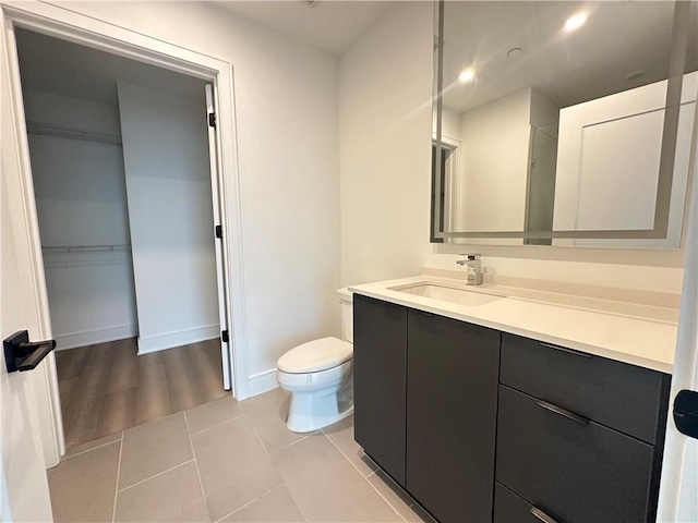 bathroom with tile patterned flooring, vanity, toilet, recessed lighting, and baseboards