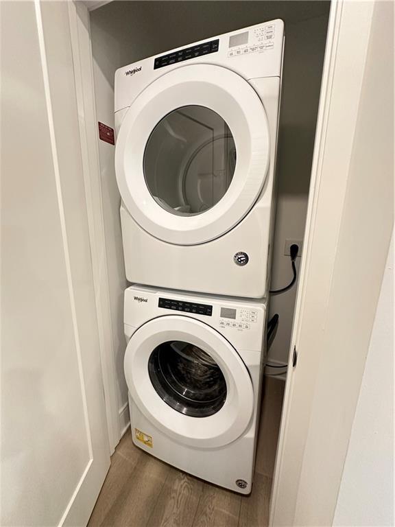 washroom featuring laundry area, wood finished floors, and stacked washer and clothes dryer