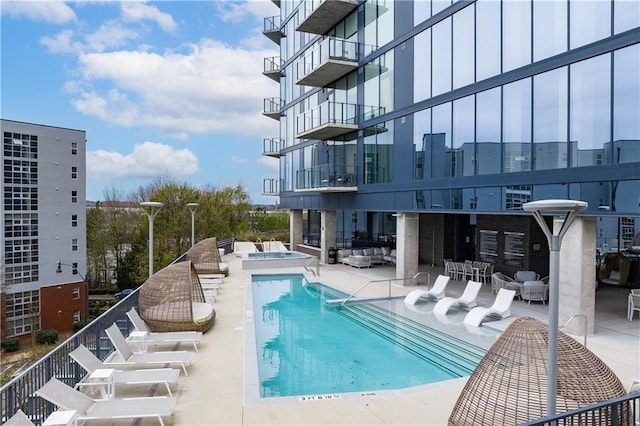 community pool featuring a hot tub, an outdoor living space, and a patio area