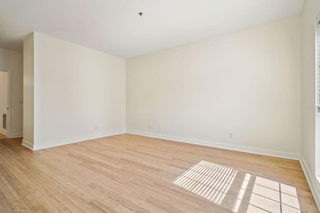 spare room featuring light wood-style floors and baseboards