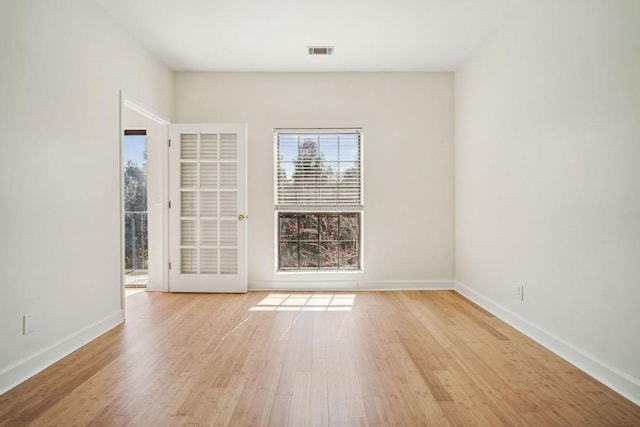 empty room with baseboards, a healthy amount of sunlight, visible vents, and light wood finished floors