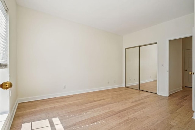 unfurnished bedroom with a closet, baseboards, and light wood finished floors