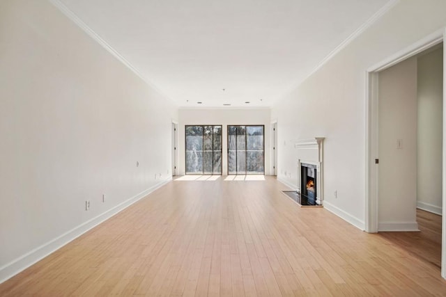 unfurnished living room with baseboards, a lit fireplace, and light wood finished floors