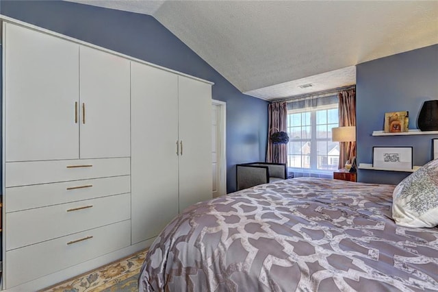 bedroom with a closet, visible vents, a textured ceiling, and lofted ceiling