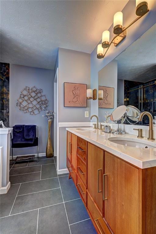 bathroom with a sink, a textured ceiling, double vanity, and tile patterned floors