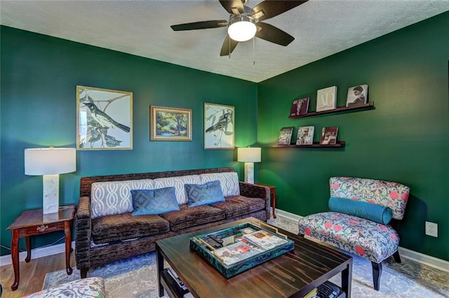 living room featuring baseboards, a textured ceiling, wood finished floors, and a ceiling fan