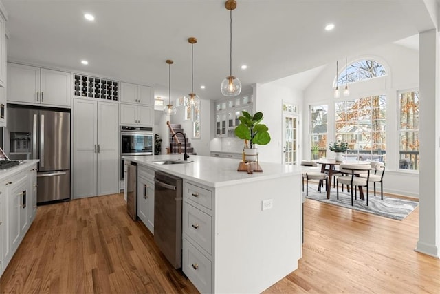 kitchen featuring sink, a center island with sink, appliances with stainless steel finishes, pendant lighting, and white cabinets