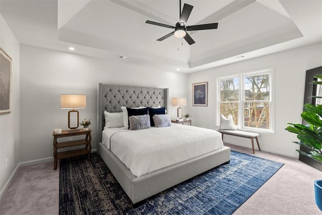 bedroom with a raised ceiling, carpet, and ceiling fan