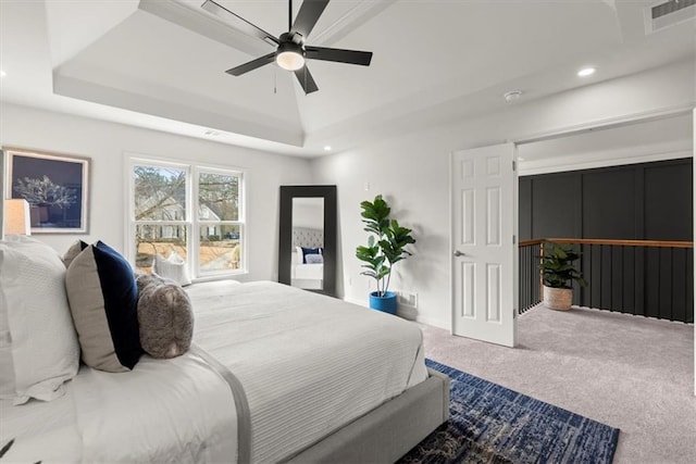 bedroom with a raised ceiling, ceiling fan, and carpet