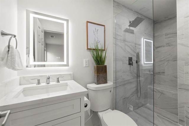 bathroom featuring vanity, a tile shower, and toilet