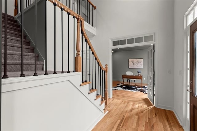 foyer with wood-type flooring and a towering ceiling