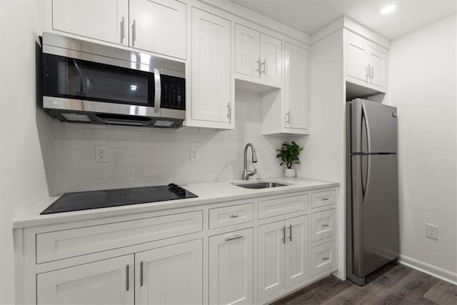 kitchen featuring white cabinetry, sink, backsplash, dark hardwood / wood-style flooring, and stainless steel appliances