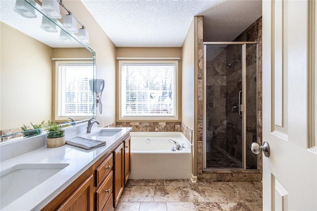 bathroom with a garden tub, double vanity, a sink, and a wealth of natural light