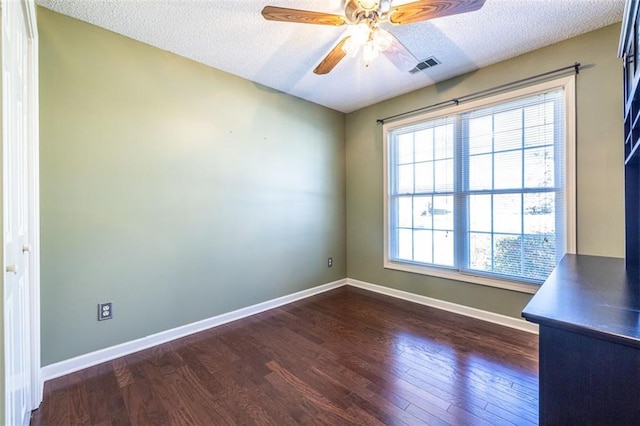 spare room with dark wood-style floors, baseboards, visible vents, and a textured ceiling