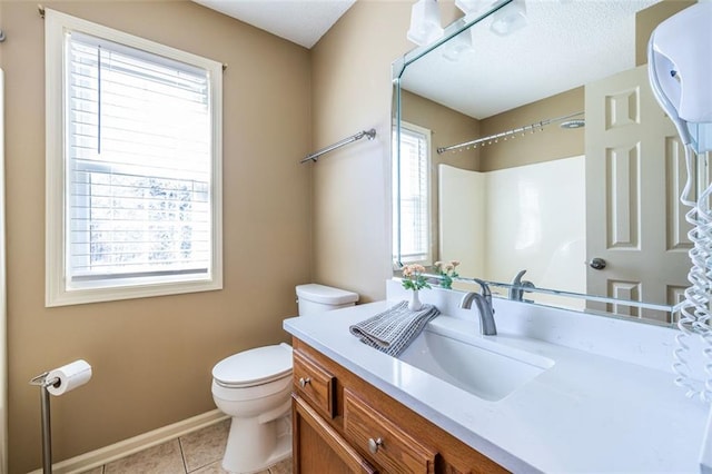 bathroom featuring tile patterned flooring, toilet, vanity, baseboards, and a shower