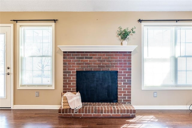 interior space with a fireplace, a textured ceiling, baseboards, and wood finished floors