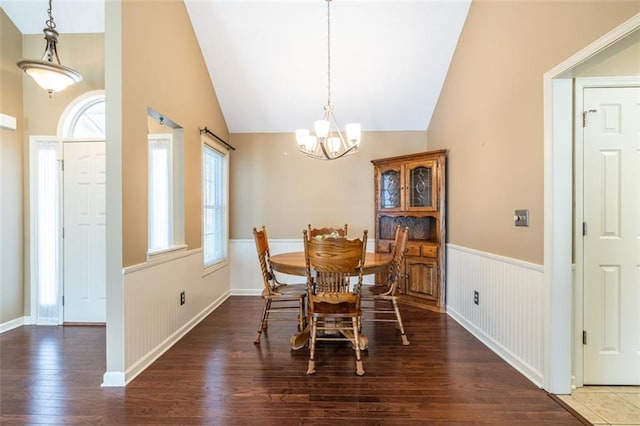 dining space with lofted ceiling, an inviting chandelier, dark wood finished floors, and wainscoting