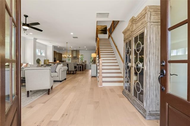 foyer entrance featuring ceiling fan with notable chandelier and light hardwood / wood-style flooring