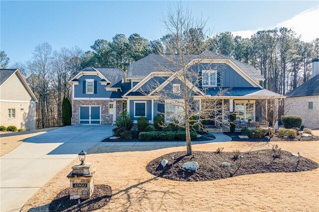 craftsman inspired home featuring concrete driveway, covered porch, brick siding, an attached garage, and board and batten siding