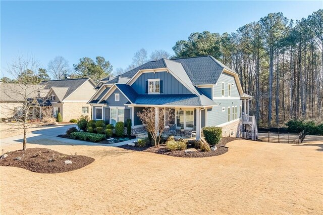 view of front of property with board and batten siding, covered porch, and stone siding