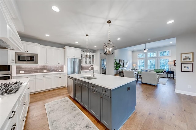 kitchen with a sink, gray cabinetry, appliances with stainless steel finishes, white cabinetry, and backsplash